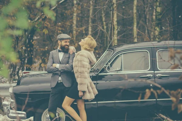 Couple in love on romantic date. Escort of girl by security. Travel and business trip or hitch hiking. Retro collection car and auto repair by mechanic driver. Bearded man and sexy woman in fur coat. — Stock Photo, Image