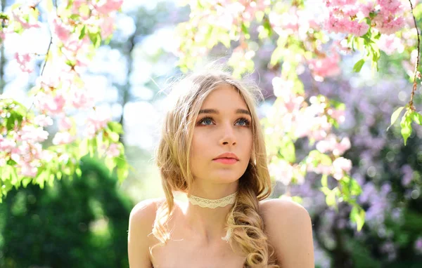 Menina no rosto sonhador, loira terna olha para a câmera, fundo da natureza, desfocada. Conceito de ternura. Jovem mulher desfrutar da natureza no jardim. Senhora caminha no parque no dia ensolarado da primavera . — Fotografia de Stock