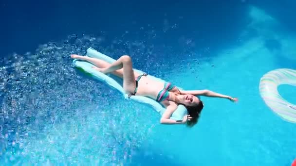 Millennial menina flutuar na piscina, festival, hotel, praia, evento sorrindo com óculos de sol durante o verão. A desfrutar do bronzeado do sol. Conceito de férias. Visão superior da jovem mulher magra em biquíni no ar azul — Vídeo de Stock