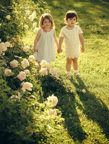 Enfants debout sur l'herbe verte à fleurs roses en fleurs — Photo