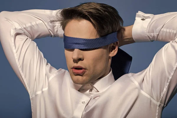 Man geblinddoekt met stropdas op blauwe achtergrond — Stockfoto