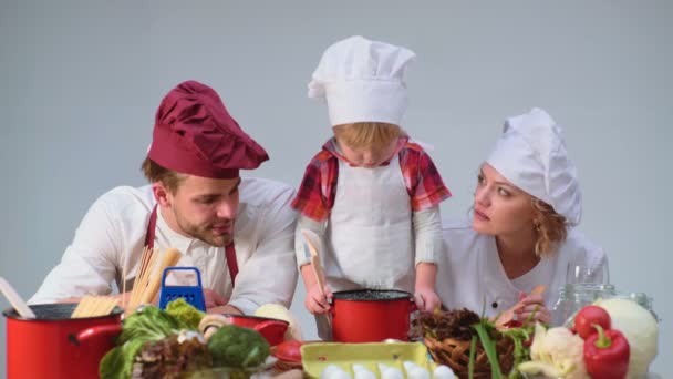 家庭烹饪厨房食品 fogetherness 概念。一家人一起在厨房做饭。可爱的小男孩和他英俊的爸爸切蔬菜和微笑, 而在厨房做饭在家 — 图库视频影像
