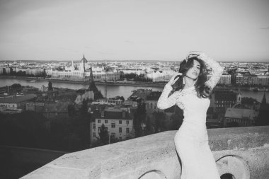 Beyaz düğün gelin kadın elbise üzerinde şehir manzaralı. Balkonda uzun saçlı gelin.