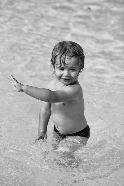 Bonito menino alegre tem banho na piscina exterior — Fotografia de Stock