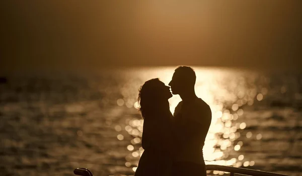 Silhouette of sensual couple kissing with sunset above sea surface on background. Couple in love on romantic date in evening at seafront, defocused, copy space. Romance and love concept. — Stock Photo, Image