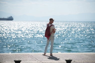 adam gezgin uzakta denizde seyir su sırt çantası ile. seyahat ve yolculuk tutkusu kavramı. yaz tatili ve maceraları. Genç adam deniz gezisi gidiyor. futute hayat kavramı