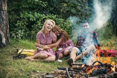 Şenlik ateşi tarafından fıkralar. Ormanda kamp arkadaşları gülüyor. İnsanlar kapsayan kamp ateşi duman