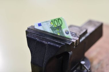 Yüz euro banknot mengene içinde sıkılmış. Mengene aracı tezgah üzerinde kağıt para düzeltmek. Euro para birimi devalüasyon veya enflasyon ve varsayılan. Finans ve Bankacılık krizi. Ekonomi ve iş sorunu