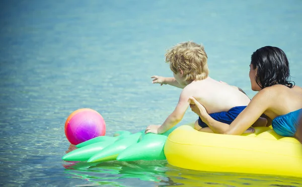 Donna con bambino nuotare sul materasso ad aria gialla in acqua in estate . — Foto Stock