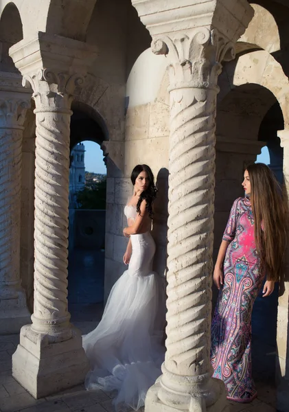 Fashion model or princess in dress. Wedding fashion and beauty. Women at stone ancient column in summer. Sexy girls in dress with stylish hair. Bride and bridesmaid at wedding ceremony in castle — Stock Photo, Image