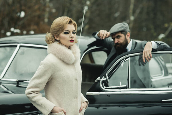 Retro collection car and auto repair by mechanic driver. Travel and business trip or hitch hiking. Bearded man and sexy woman in coat. Escort of girl by security. Couple break up at a meeting.