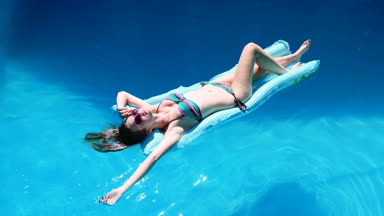 bin yıllık kız float Havuzu, Festivali, otel, plaj, yaz aylarında güneş gözlüğü üzerinde gülümseyen olay. Güneş zevk. Tatil kavramı. Mavi Hava ince genç kadının bikini Üstten Görünüm