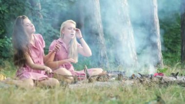PIN günbatımında bir piknik Park eğlenmek tarzında iki genç kadın. Yaz, tatil, tatil, mutlu insanlar kavramı - kız gülümsüyor. Piknik üzerindeki Girlfriends.