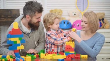 Genç aile oyun odası. Aile kavramı seviyorum. Anne, baba ve çocuk oyuncakları ile dışarı plastik blokları inşa. Anne ve oğlu gülümseyen, tuğla yapılar yapmak.