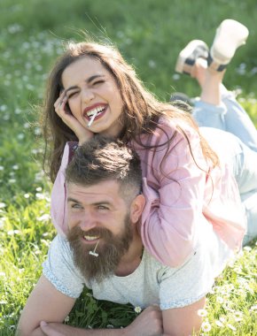 Erkek ve kadın üzerinde çim döşeme bahar günü. Gülümseyen yüzler doğa üzerinde arka plan açık havada, Sigara çift. Sigara alışkanlığı kavramı. Aşık çift harcamak zaman açık havada ve yasaktır.