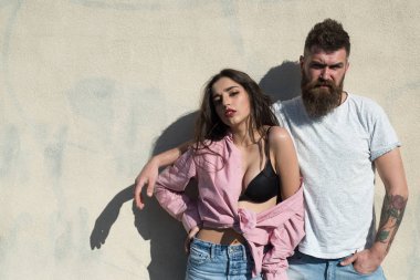 Sakal ve Bayan sıcak güneşli günde kibirli yüzünde olan adam. Çift ısı yaz gününde, arka plan, kopya alanı duvarda uğrar. Kız açılarak forması altında siyah sutyen takıyor. Sıcak ve seksi kavramı.