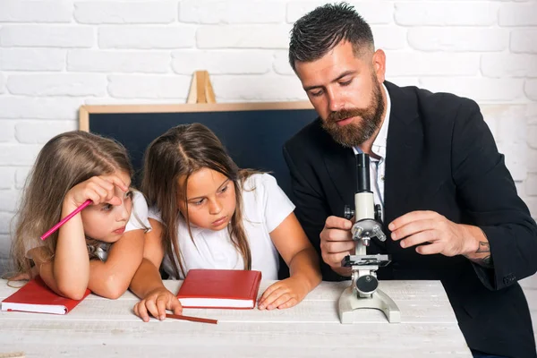 回到学校和家庭教育 生物课 在实验室里用显微镜学习 学校时间的姐妹和父亲 知识日的教育 男教师实验科学与女孩 — 图库照片