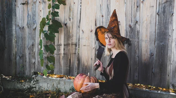 Halloweenhäxan. Häxan poserar med pumpa i svart hatt. Galna halloween. Glad gotiska unga kvinna i häxa halloween kostym. Halloween-konceptet. — Stockfoto