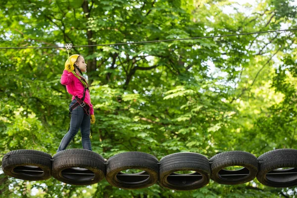 Des enfants actifs. Casque - équipement de sécurité pour le jeu des enfants. Filet de fret grimpant et rondin suspendu. Activités Eco Resort. Sûr Escalade sport extrême avec casque. Des cordes hautes marchent . — Photo