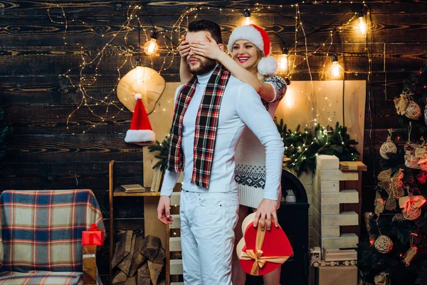 Glada leende flickvän täcker sina pojkvänner ögon förbereder sig för honom nytt år eller julklapp. Gott nytt år. Julafton. Nytt år. Hemma. Fira jul tillsammans koncept. — Stockfoto