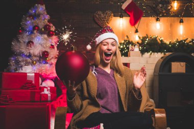 Noel ve Noel hediyeleri aşkına. Kadın Noel 'i. Göz kırp. Çılgın komik surat. Genç kadın göz kırpıyor. Komik somurtkan. Noel kadınının elinde bomba var. Yaratıcı patlama. Bomba duyguları.