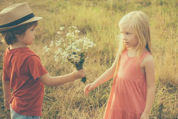 Recuerdos de la infancia. Niños divirtiéndose en el campo contra la naturaleza. Hermosa pequeña pareja - niño y niña abrazando. El chico se divierte en el campo de primavera. Tarjeta de San Valentín. Tarjeta de felicitación de arte festivo — Foto de Stock