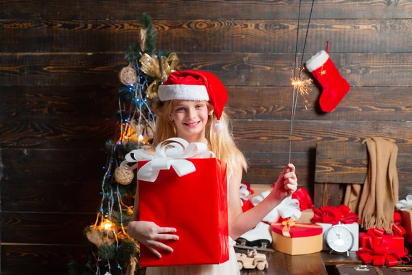 Noel hediyesi tutan komik çocuk. Noel çocukları. Mutlu Noeller ve mutlu tatiller. Noel Baba şapkalı küçük mutlu ergenler Noel 'i kutlayın. Kış akşamı evde. — Stok fotoğraf
