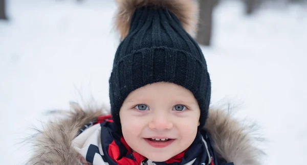 Netter kleiner Junge im Winterpark. Weihnachts- und Neujahrsferien. schneereiches kaltes Wetter. Winterurlaub. wunderschöne Winternatur. Kleiner Junge in warmer Winterkleidung hat Spaß. — Stockfoto