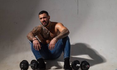 Dambılla egzersiz yapan kaslı bir adam. Antrenmanından memnun. Spor yaşam tarzı. Spor motivasyonu. Yakışıklı adam antrenman yapıyor. Spor salonu. Dövmeli bir erkek..