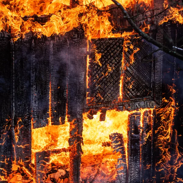 Огонь разрушает обугленный сожженный дом. Обгоревший в пламени по ночам. Пожар везде и дым в жилом районе ночью. Опасный огонь. Весь дом и двор в огне . — стоковое фото