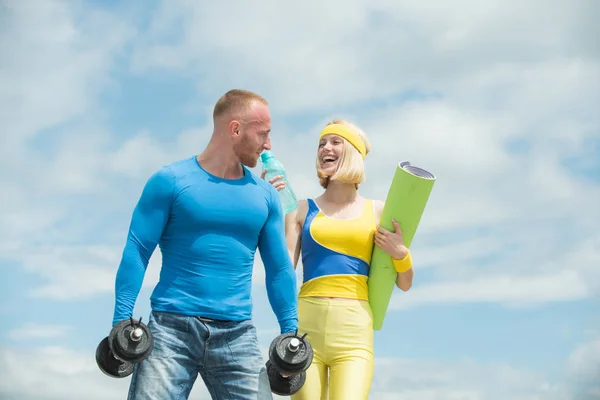 Beautiful cheerful smiling woman workout with her sport coach. Loving couple doing fitness at fresh air outdoors. Successful teamwork at blue sky background.