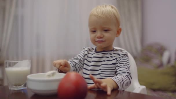 Baby kind eet rode appel. Lachend vrolijke schattige baby die fruit eet in de keuken. Kind jongen eet gezond voedsel thuis. — Stockvideo