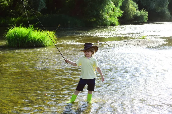 Pesca infantil. Niño aprendiendo a pescar sosteniendo una caña en un río. Niño pescador con caña de pescar. Hombre joven pesca con mosca . —  Fotos de Stock