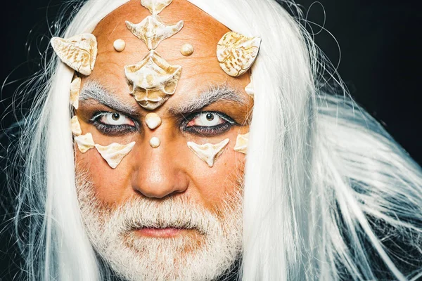 Anciano sosteniendo dos cuernos rojos. Demonio diabólico ardiente convoca fuerzas malignas y abre el infierno. Hombre vampiro malvado. Concepto de terror diabólico. Viejo barbudo vestido como un monstruo de Halloween . — Foto de Stock