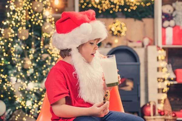 Mleko i pierniki ciasteczko dla Mikołaja na tle światła Bożego Narodzenia. Mały Mikołaj zbierając ciastko i szklankę mleka w domu. — Zdjęcie stockowe