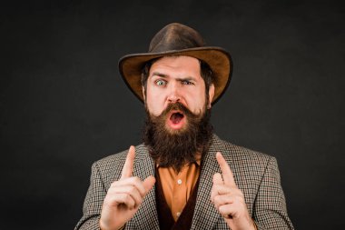 Funny brutal bearded hipster on isolated background. Close up photo of handsome funny man with beard in suit. Hand with fingers set into gun gesture.