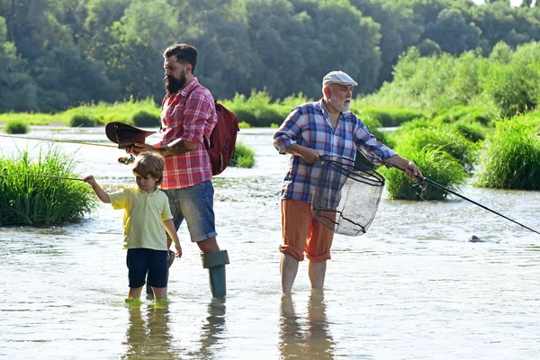 Giornata degli uomini. Un legame familiare. Pescatore a mosca con canna da pesca a mosca nel fiume. Pesca a mosca della trota. Nonno e nipote. bisnonno e pronipote . — Foto Stock