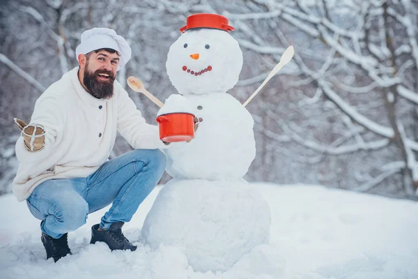 Cocinero divertido de Navidad. Preparación de Navidad - hombre barbudo divertido con muñeco de nieve. El hombre está feliz por el año nuevo. Hipster Santa Claus . — Foto de Stock