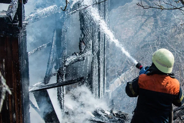 Настоящий храбрый герой борется с огнем огнетушителем. Сильный и храбрый пожарный спасает горящее здание. Концепция работы пожарного. Пожарные используют воду в пожаротушении . — стоковое фото