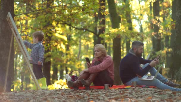 Sarı doğada mutlu bir aile. Neşeli aile dışarıda eğleniyor. Mutlu anne baba ve oğul sonbahar parkında. Aile sonbahar yapraklarında oturuyor.. — Stok video