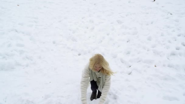 Mujer joven rubia Hacer bola de nieve. Juego de invierno con nieve. Mujer de invierno jugar con bola de nieve. Chica feliz con bola de nieve de pie en invierno paisaje de Navidad . — Vídeo de stock