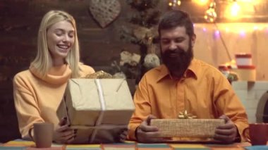 Tatlı çift evde Noel hediyelerini açıyor. Genç çift Noel hediyelerini kağıda sarıyorlar. Hediyeler. Gülümseyen çift Noel hediyesini açıyor.