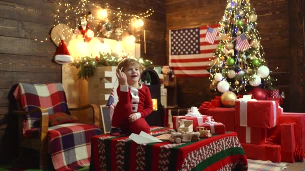 Vrolijk kerstfeest en gelukkig nieuwjaar in Amerika, Usa. Kerstviering. Amerikaans kind geniet van de vakantie. Gift emoties. — Stockvideo