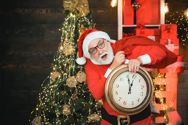 Veselý vánoční Santa s hodinami. Fotografie Santy, jak drží hodiny pět minut do půlnoci. Santa Claus se dívá na hodinky. — Stock fotografie