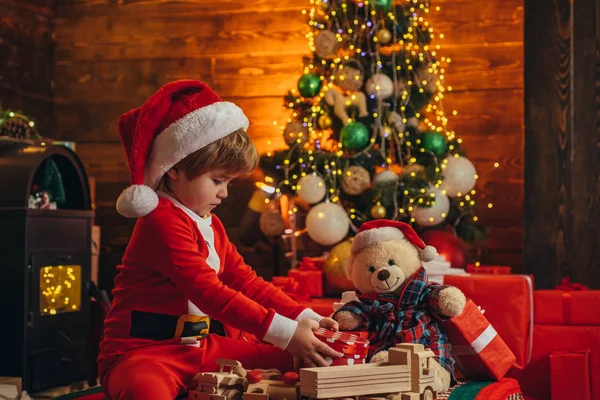 Little boy with Christmas presents. Holidays and winter childhood concept. Gifts service. Gifts for winter holidays at fire place. Happy holiday. Family winter holidays and people concept.