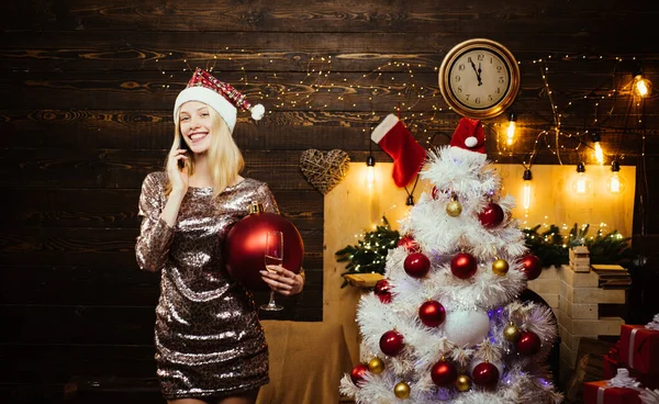 クリスマスツリー上のエレガントな女性が背景に点灯します。家でクリスマスツリーを飾る笑顔の女性。女性の新年の前夜. — ストック写真