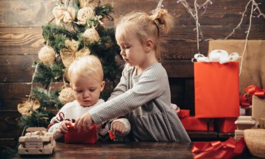 Noel ve yeni yılda hediyeleri açmak. Noel kartı. Ahşap arka planda yeteneği olan bir portre çocuğu. Gülümseyen çocuk oturma odasında Noel ağacının arkasından dikizliyor..