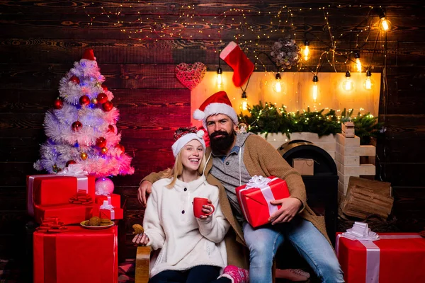 Nytt år familj med nuvarande julklapp framför julgranen. Stilig skäggiga hipster Santa med leende positiva unga kvinna. Uttryck och människor-konceptet. — Stockfoto