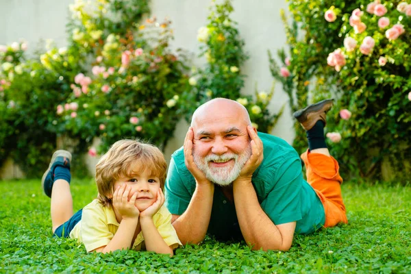 Семейное лето и активный отдых. Отец и дедушка. Милый мальчик обнимает дедушку. Счастливые отец и сын на лугу летом . — стоковое фото