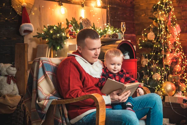 Mutlu Noeller ve mutlu yıllar. Noel sahnesi - Baba küçük oğlu için kitap okuyor. Aile Noel zamanı. Ebeveyn hedefleri. — Stok fotoğraf
